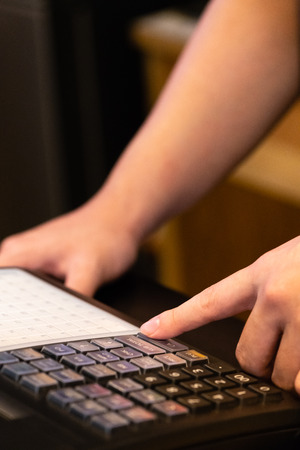 cash register installed on counter for accepting order from customer.sales man entering amount on electronic cash register in coffee shop and retail store.restaurant cashier typing on cash register.の写真素材