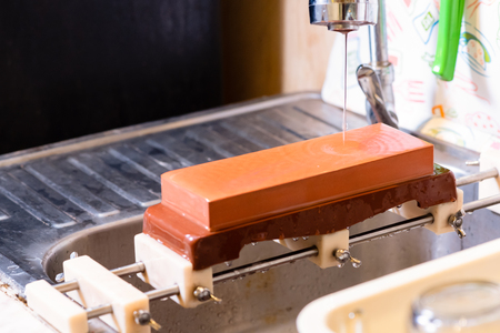 woman professional chef hands hold knife for whetting on whetstone.premium professional stone from japan.knife sharpening process with traditional sharpener stone for knife sharpen edge in restaurant.の写真素材