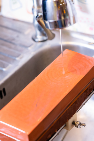 woman professional chef hands hold knife for whetting on whetstone.premium professional stone from japan.knife sharpening process with traditional sharpener stone for knife sharpen edge in restaurant.の写真素材