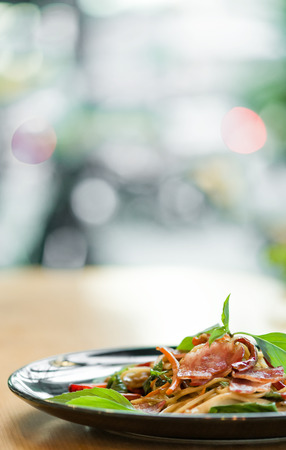delicious spicy spaghetti dried chilli and basil sauce with bacon and mushroom ,beautiful close up spicy spaghetti bacon on black plate with some space for text.の写真素材
