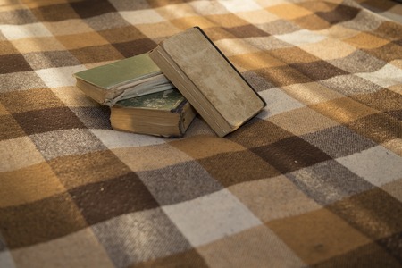 stack of battered old books on a plaid