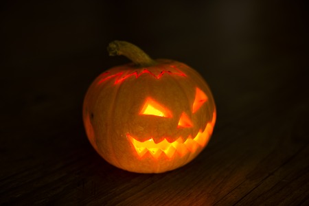 Illuminated cute halloween pumpkin on black backgroundの写真素材