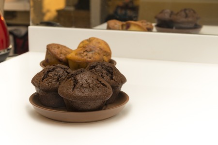 Chocolate muffins in a brown plate on a background of snow-white kitchenの写真素材