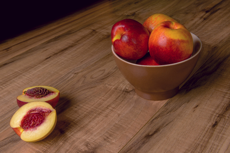 Fresh ripe peaches on a brown plate, a wooden tableの写真素材