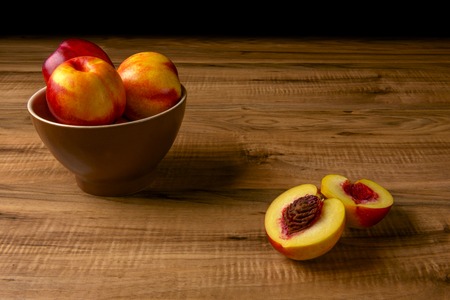 Fresh ripe peaches on a brown plate, a wooden tableの写真素材
