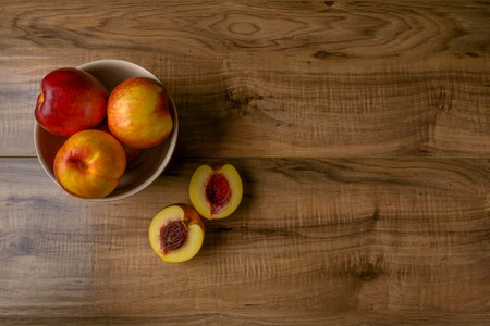 Fresh ripe peaches on a brown plate, a wooden tableの写真素材