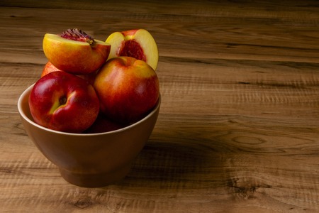 Fresh ripe peaches on a brown plate, a wooden tableの写真素材