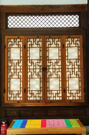 Korea Hanok house interior with craved windows and stool covered by traditional fabric in Seoul, South Koreaのeditorial素材