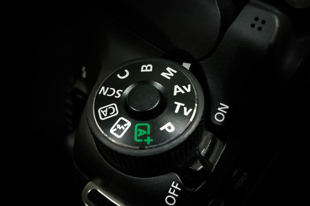 Control dial on a DSLR camera, close up image isolated on black backgroundの写真素材