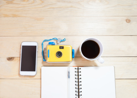 Office wood desh with notebook phone coffee and film cameraの写真素材