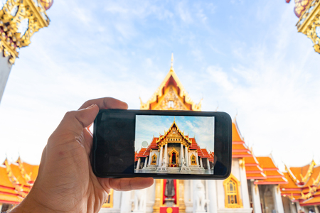 Taking photo Thai Marble Temple (Wat Benchamabophit Dusitvanaram) with mobile phone in Bangkok, Thailandの写真素材