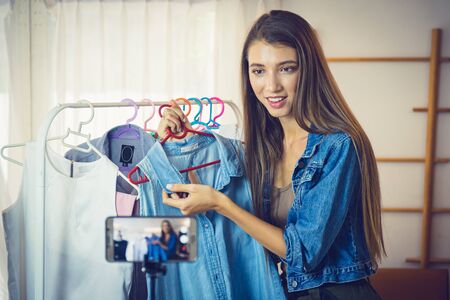 Young girl selling clothes online by live streaming from mobile phone.の写真素材