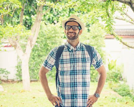 Happy young bearded wearing eye glasses man carrying his backpack preparing to travel.の写真素材