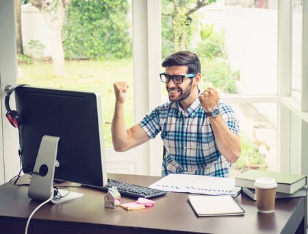 Casual young caucasian businessman at his desk in winning concept.の写真素材