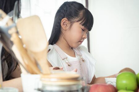 Happy moment together! Asian mother and daugter prepare their food together in the kitchen.の写真素材
