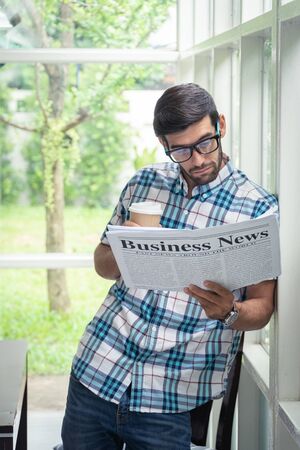 Young casual businessman reading business news in the morning at home office.の写真素材