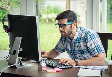 Good looking young business man working on the internet at homeの写真素材