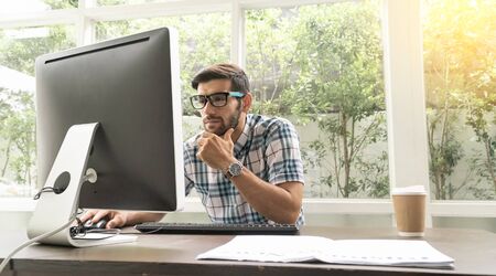 Good looking young business man working on the internet at homeの写真素材