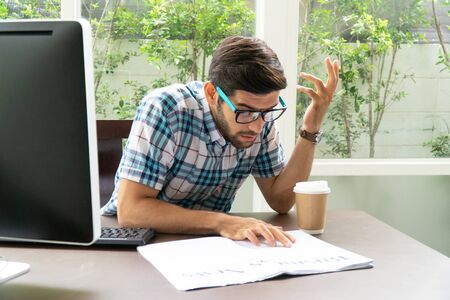 Young casual businessman reading business news in the morning at home office.の写真素材