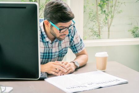 Young casual businessman reading business news in the morning at home office.の写真素材