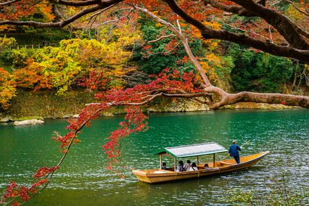Boatman paddling the boat at Arashiyama forest view in the Autumn along Katsura river. Kyoto, Japan.の写真素材