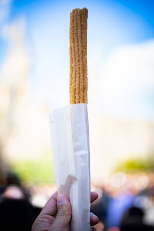 Churros stick - the traditional Spain dessert in hand holding with background copy space.の写真素材