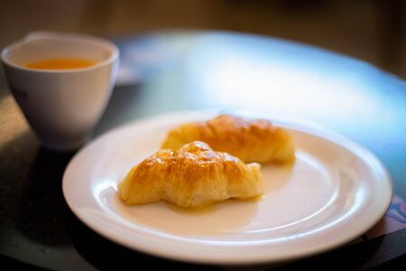 freshly baked French bread croissant on white plate. with coffee cup.の写真素材