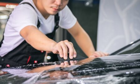 Car wrapping specialist putting vinyl foil or film on car for protection. Selective focused - film effectedの写真素材
