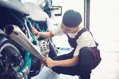 Asian mechanic man fixing the retro motorcycle in the garage. Film effected - Selective focusedの写真素材