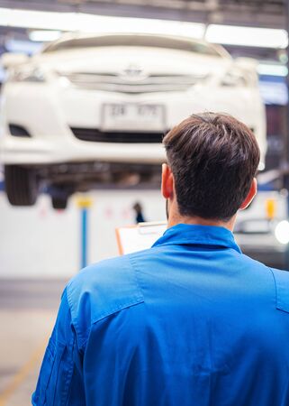 Mechanic checking car and write down in the paper on clipboard. Auto car service conceptsの写真素材