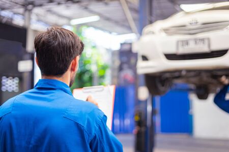 Mechanic checking car and write down in the paper on clipboard. Auto car service conceptsの写真素材
