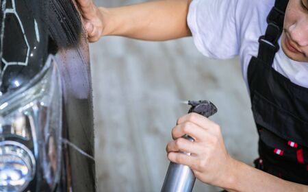 Car cleaning auto service : the man sprays water - car detailing conceptsの写真素材