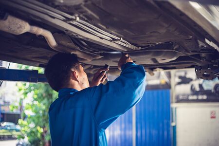 Mechanic reparing the car in the workshop garage. Car auto services conceptsの写真素材