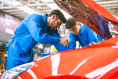 Mechanics checking and repairing the car in a blue suit. Car auto services conceptsの写真素材