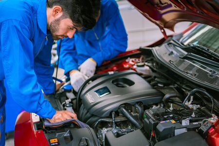 Mechanics checking and repairing the car in a blue suit. Car auto services conceptsの写真素材