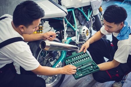 Asian mechanic man fixing the retro motorcycle in the garage. Film effected - Selective focusedの写真素材