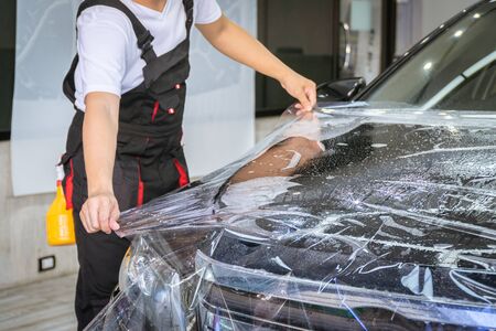 Car wrapping specialist putting vinyl foil or film on car for protection. Selective focused - film effectedの写真素材
