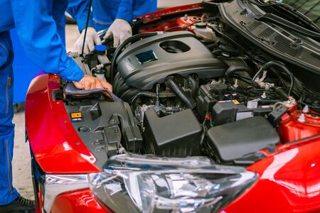 Mechanics checking and repairing the car in a blue suit. Car auto services conceptsの写真素材