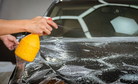 Car wrapping specialist putting vinyl foil or film on car for protection. Selective focused - film effectedの写真素材