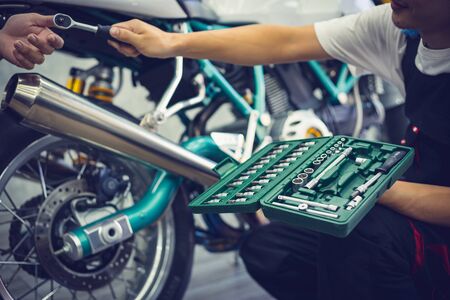 Asian mechanic man fixing the retro motorcycle in the garage. Film effected - Selective focusedの写真素材