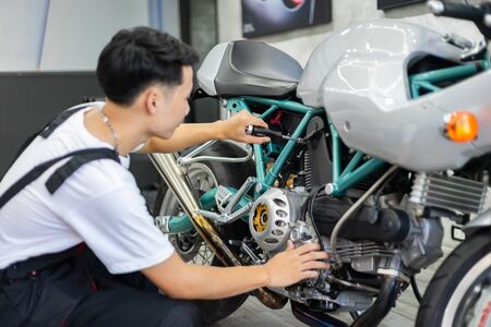 Asian mechanic man fixing the retro motorcycle in the garageの写真素材