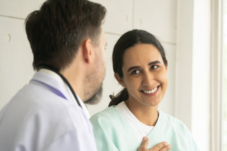 Relaxing Caucasian male physician with Hispanic female patient. The medical healthcare exam and check-up with the doctor concept.の写真素材