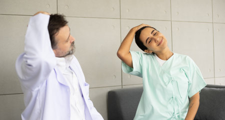 Caucasian doctor working as physiotherapist for stretching and rehabilitation Hispanic patient's injury and painful body. Medical and healthcare recovery at hospital concept.の写真素材