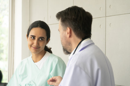 Relaxing Caucasian male physician with Hispanic female patient. The medical healthcare exam and check-up with the doctor concept.の写真素材