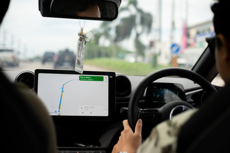 Back seat view of traveler man driver driving an EV car and using GPS navigation map on tablet touch screen during road trip.の写真素材