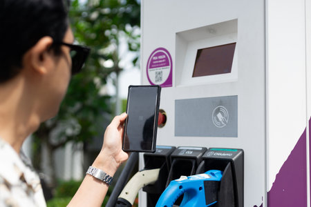 Electric car charging at the station. Sustainability and renewable energy concept. Electric vehicle (EV) fuel advance, save the earth conception. QR code payment with mobile phoneの写真素材