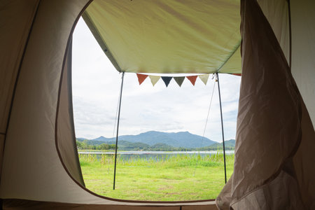 Camping picnic green tent campground in outdoor park lake. Camper while campsite in mountain and lake nature background at summer trip camp. Adventure Travel and Vacation conceptの写真素材