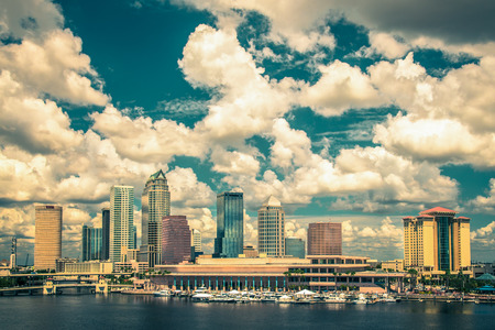 Vintage toned image of  Tampa Florida skyline with sun, clouds and reflectionsの写真素材