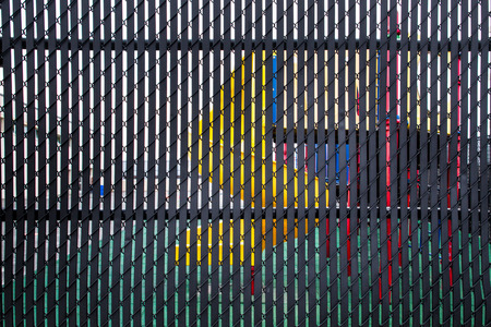Playground equipment seen through slats of metal privacy fence