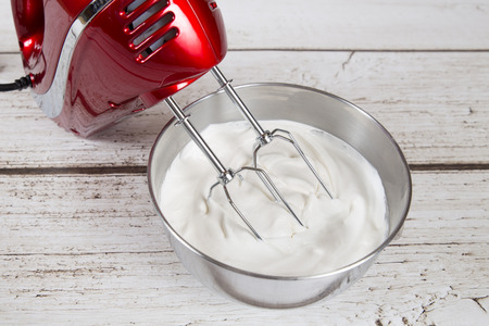 Electric hand mixer with whipped creamの写真素材